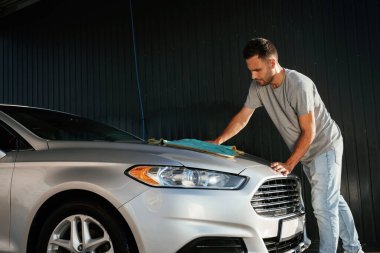 Yandan bak, otomobili parlatmak için bez kullan. Adam dışarıda arabasıyla bekliyor..