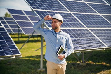 Dijital tablet hazır. Gündüz vakti fotovoltaik güneş panelleri olan bir mühendis..