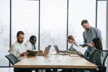 Masada bir sürü dizüstü bilgisayar var. Ofis çalışanlarından oluşan ekip içeride bir arada..