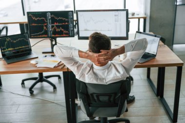 Ellerin başının arkasında oturuyorsun. İşadamı bilgisayar başında ve ofiste çalışıyor..