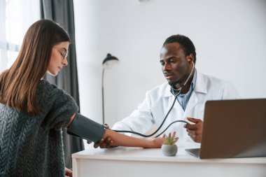 Müşteri hizmetleri. Bir doktor genç bir kadının kan basıncını ölçer..