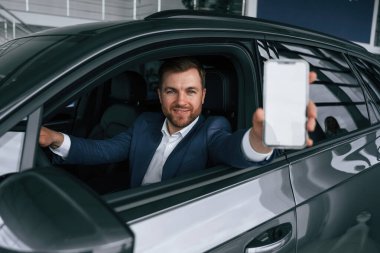 Ekranda kopya alanı olan akıllı telefon. İşadamı yeni arabasında..