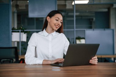 Dizüstü bilgisayarla çalışıyor. İş kadını ofisin içinde..