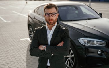 Siyah takım ve beyaz gömlek. İş adamı arabasının yanında..