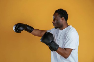 Eldivenli profesyonel boksör. Siyah adam sarı arka plana karşı..