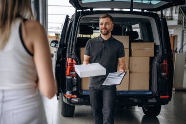 Müşteri siparişini alıyor. Kadın teslimatçıyla, arabayla..