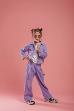 Elindeki renkli şeker. Şirin küçük kız pembe arka plana karşı..