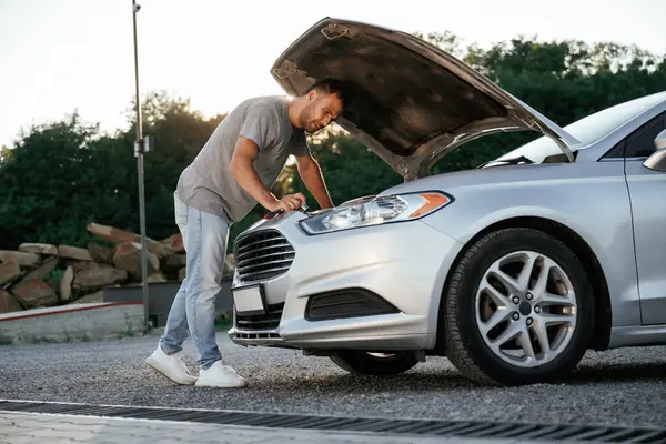 Sorun, bozuk otomobili tamir etmek ve onarmak. Adam dışarıda arabasıyla bekliyor..