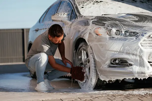 Otomobili yıkama işlemi. Adam dışarıda arabasıyla bekliyor..