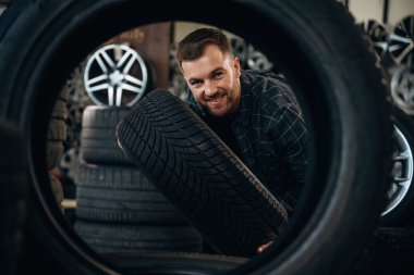 Lastik deliğinden bakıyor. Erkek işçi tekerlekleri olan bakım istasyonudur..