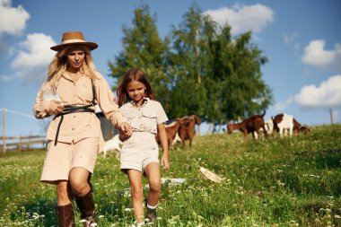 İleriye doğru yürüyorum. Anne ve kızı çiftlikte keçilerle birlikte..