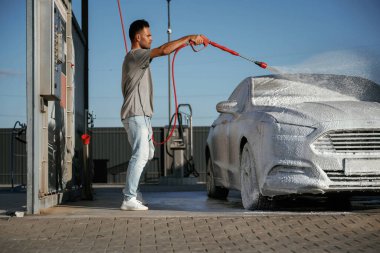 Yüksek basınç, otomobili yıkamak. Adam dışarıda arabasıyla bekliyor..