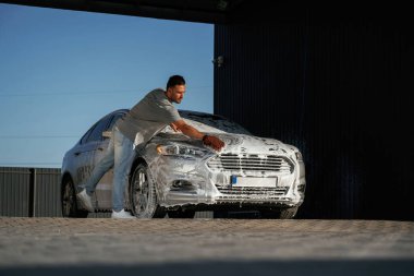 Köpük yıkılıyor, otomobil sabun içinde. Adam dışarıda arabasıyla bekliyor..