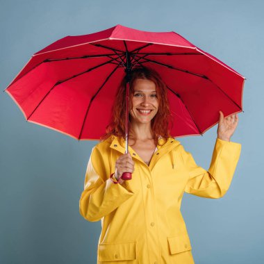 Kırmızı şemsiye ve sarı yağmurluk. Kadın stüdyoda arka planda..