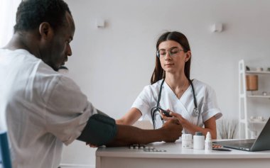 Kadın doktor bir erkeğin kan basıncını ölçer..