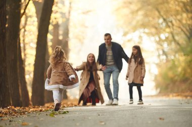 Hafta sonu yürüyüşü. Mutlu anne, baba ve iki kız çocuk ailesi sonbahar parkında, ormanda, yolda.