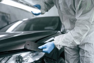 Doğru rengi seçiyorum. Garaj çalışanı arabanın aydınlatma ve kontrol yüzeyini tutuyor..