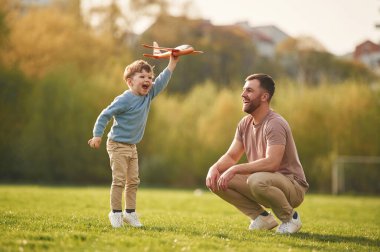 Hafta sonu aktiviteleri. Oyuncak uçakla oynamak. Mutlu baba ve oğul yazın sahada eğleniyorlar..