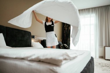 Yatak için beyaz yastık kılıfı. Genç oda hizmetçisi otel odasında..