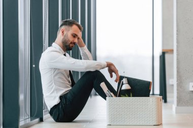 Yerde oturduğum için kendimi kötü hissediyorum. İşsiz adam kovulduktan sonra kişisel eşyalarıyla birlikte..