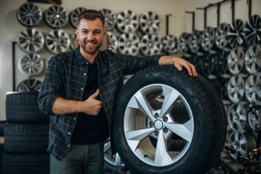 Gülümseme, pozitif yüz ifadesi, el hareketi. Tekerlekleri ve tekerlekleri olan tamirci var..