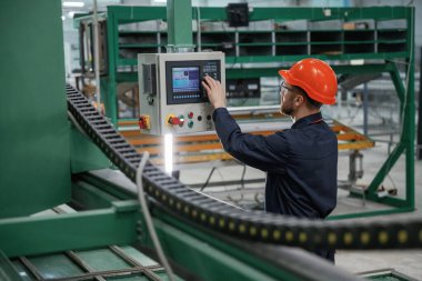 Yeşil renkli makine, operatör meşgul. Fabrika işçisi kasketli bir şekilde içeride..