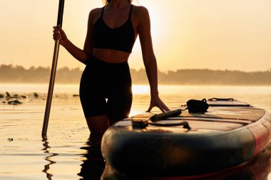 Neredeyse akşam oldu, gün batımı. Genç kadın gölde yemek masasında..