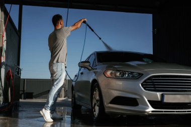 Yüksek basınç, otomobili yıkamak. Adam dışarıda arabasıyla bekliyor..