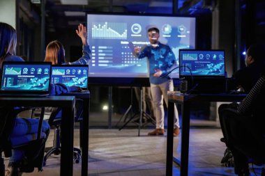 Resmi kıyafetlerle. Erkek işletme eğitmeni projektöre karşı, insanlara öğretiyor..