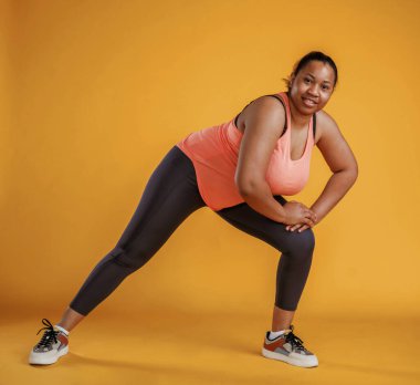Fitness yapıyorum. Afrikalı Amerikalı kadın sarı arka planda stüdyoda..