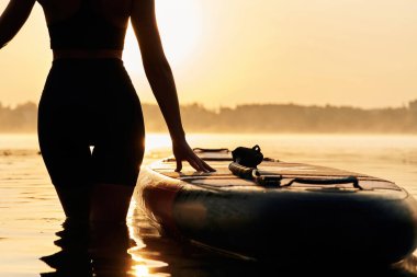 Siyah siluet, gün batımı, aydınlatma. Genç kadın gölde yemek masasında..