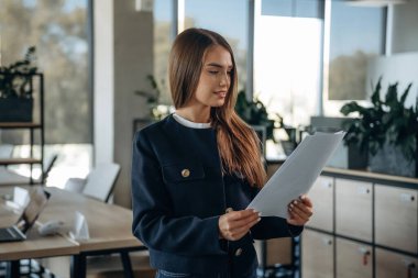 Belgeler ellerde, kağıtlar. Ofiste güzel bir kadın çalışıyor..