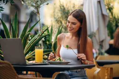 Restoranın dışında. Güzel genç bayan masanın yanında oturuyor..