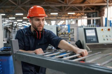 Makinelerle çalışmak. Fabrika işçisi kasketli bir şekilde içeride..