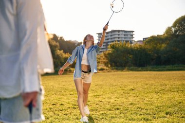 Günlük kıyafetlerle. İki kadın sahada badminton raketleriyle eğleniyor..