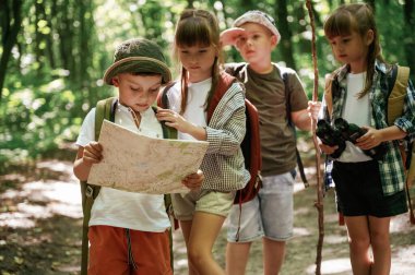 Akıllı çocuk haritayı okuyor. Çocuklar yazın gündüz vakti ormanda..