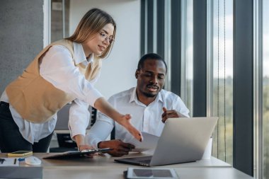 Dizüstü bilgisayarın yanında. Ofiste iki iş adamı birlikte çalışıyor..