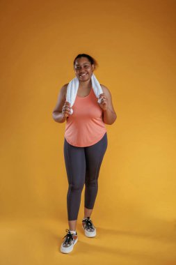 Egzersizden sonra beyaz havluyla. Afrikalı Amerikalı kadın sarı arka planda stüdyoda..