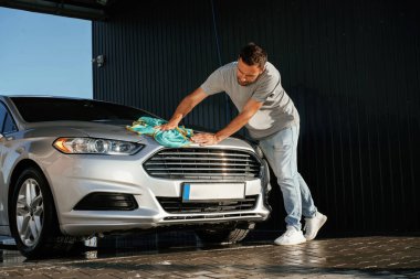 Ellerinde bezle. Adam dışarıda otomobille dolaşıyor..