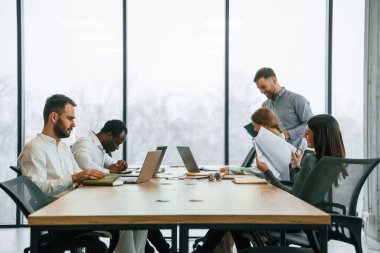 Masada bir sürü dizüstü bilgisayar var. Ofis çalışanlarından oluşan ekip içeride bir arada..