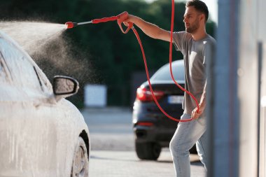 Otomobili yıkıyorum. Adam dışarıda arabasıyla bekliyor..