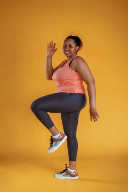 Fitness yapıyorum. Afrikalı Amerikalı kadın sarı arka planda stüdyoda..
