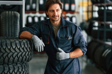 Bir sürü lastiği olan bir depo. Lastik tamir servisinde adam var..