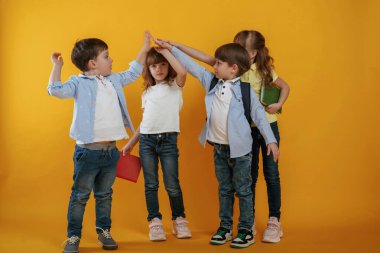 Çak bir beşlik. Çocuklar sarı arka plana karşı birlikte..