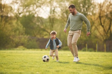 Futbol topuyla. Mutlu baba ve oğul yazın sahada eğleniyorlar..