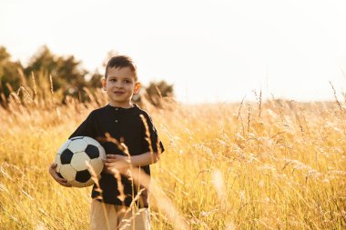 Futbol topunu tutuyorum. Küçük çocuk yazın dışarıda eğleniyor..