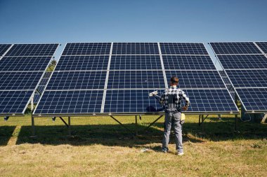 Arka manzara, bakım. Gündüz vakti fotovoltaik güneş panelleri olan bir mühendis..