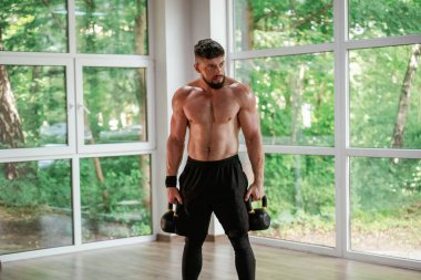 Ağır halterlerle. Güçlü kaslı adam spor salonunda çalışıyor..