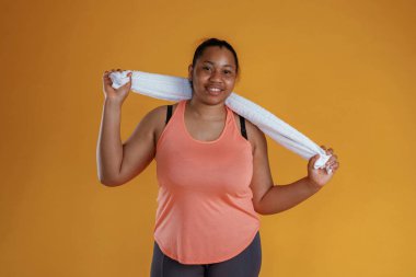 Egzersizden sonra beyaz havluyla. Afrikalı Amerikalı kadın sarı arka planda stüdyoda..