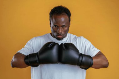 Güç kavramı. Boks eldivenleriyle. Siyah adam sarı arka plana karşı..
